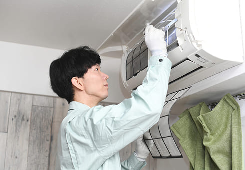 エアコンのフィルター清掃をしている男性従業員イメージ